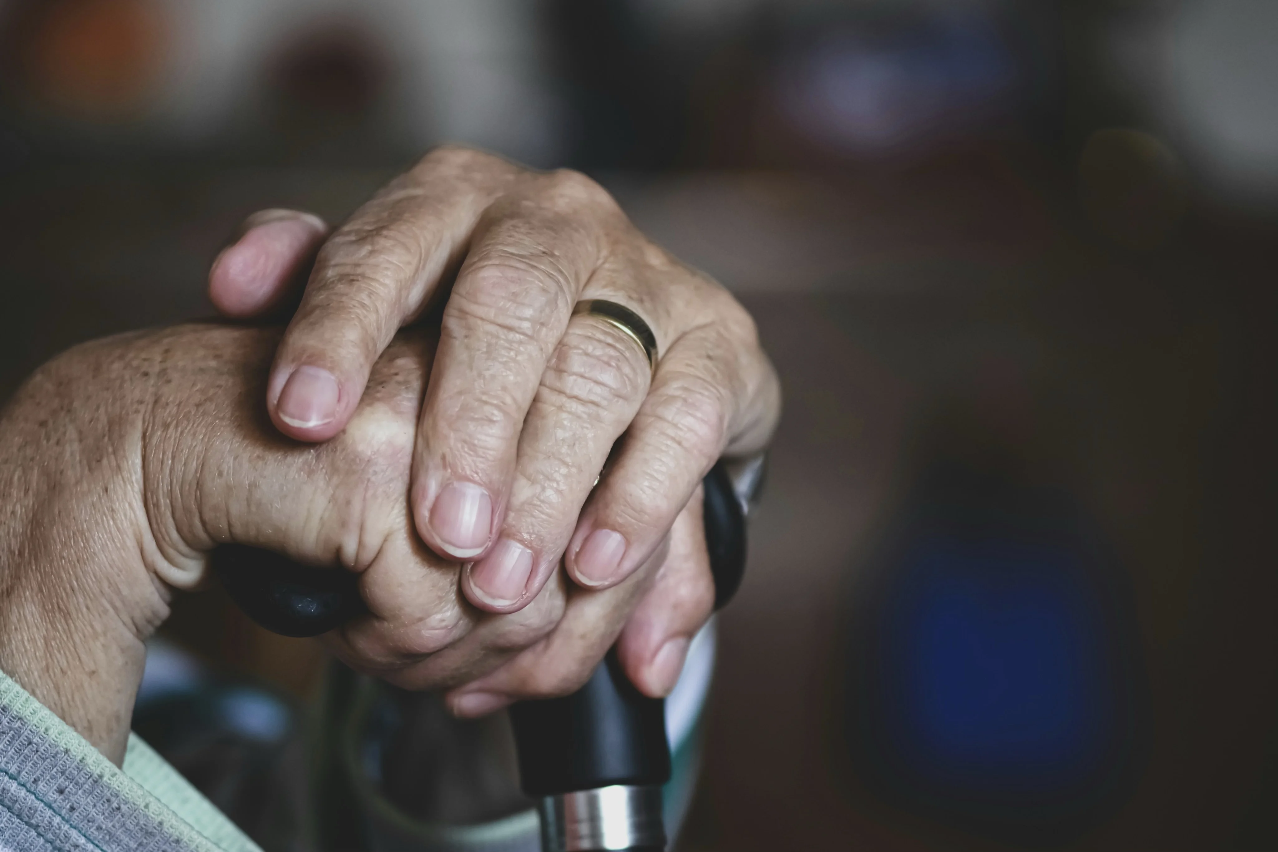 An older person and a family member completing an Attendance Allowance application form together at a kitchen table.