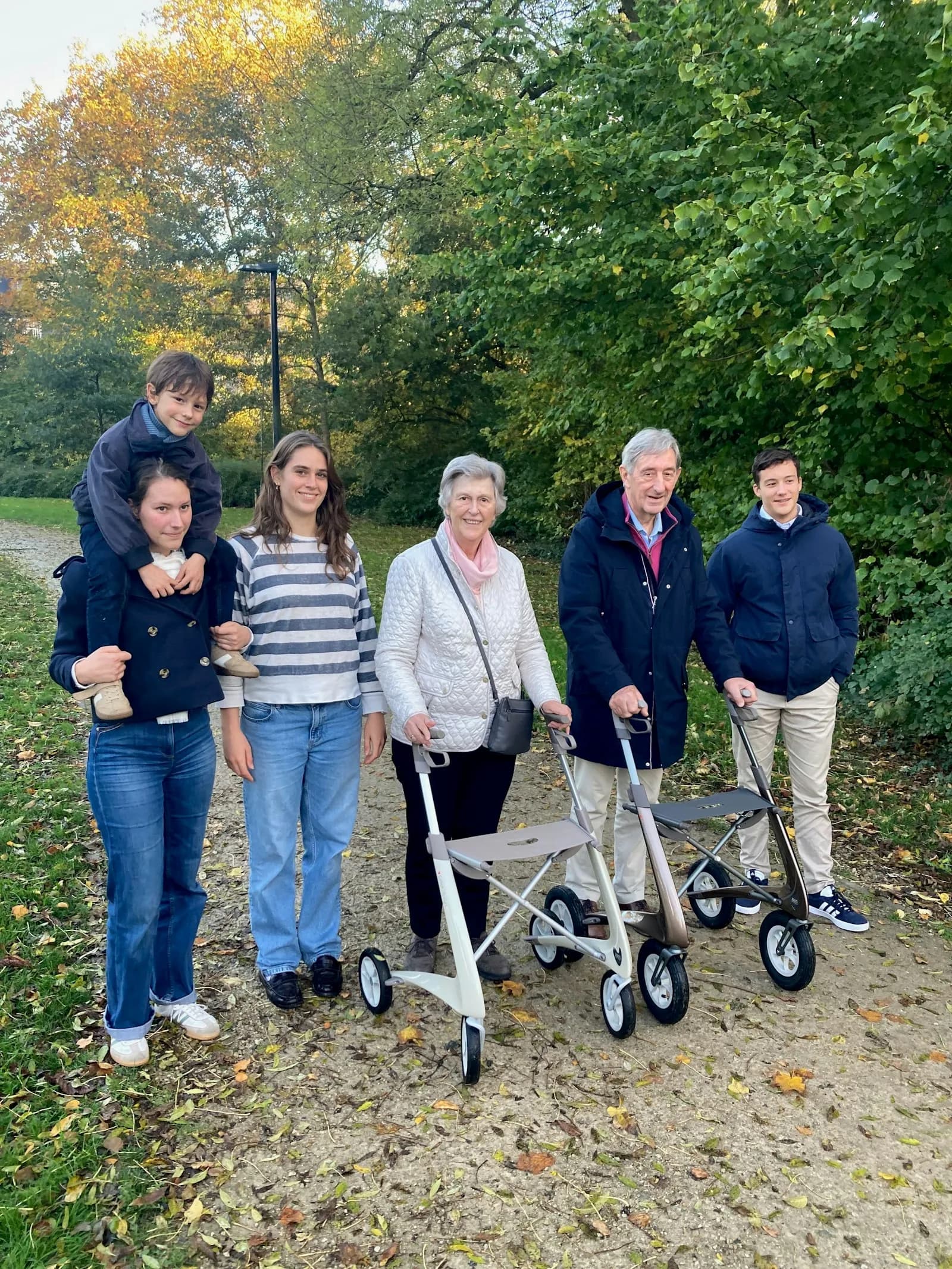 A multi-generational family walking together along a path — three generations sharing the practical and emotional work of family caring that sits behind every Carer's Allowance claim.