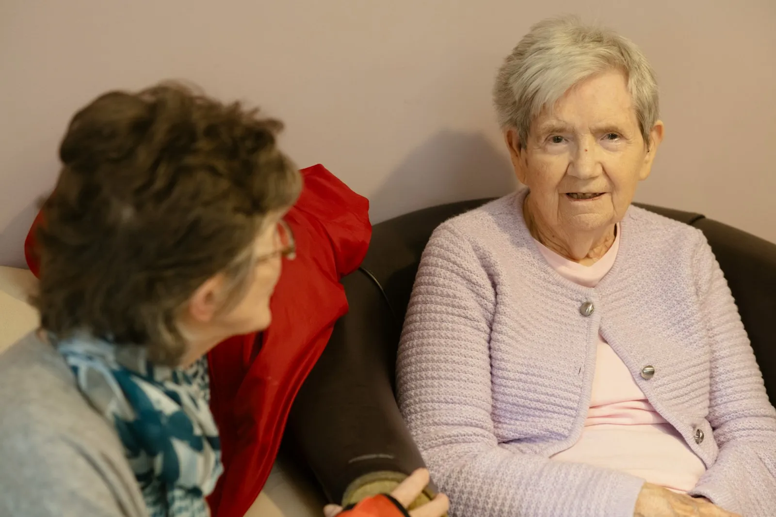 Two older women sitting together and talking quietly — the everyday companionship and supervision that often counts toward the 35-hour-a-week Carer's Allowance qualifying threshold.