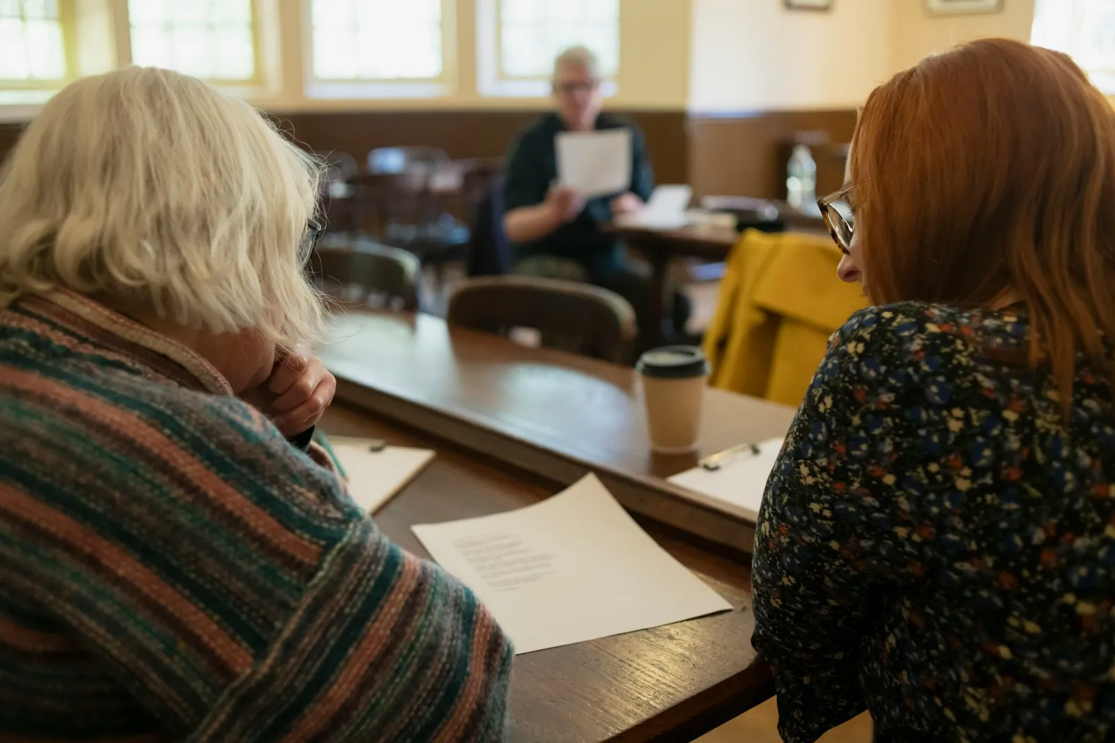 Two women sitting at a table with paperwork in front of them — the household conversation that typically follows the first home care invoice, and the moment to ask about NHS Continuing Healthcare funding.