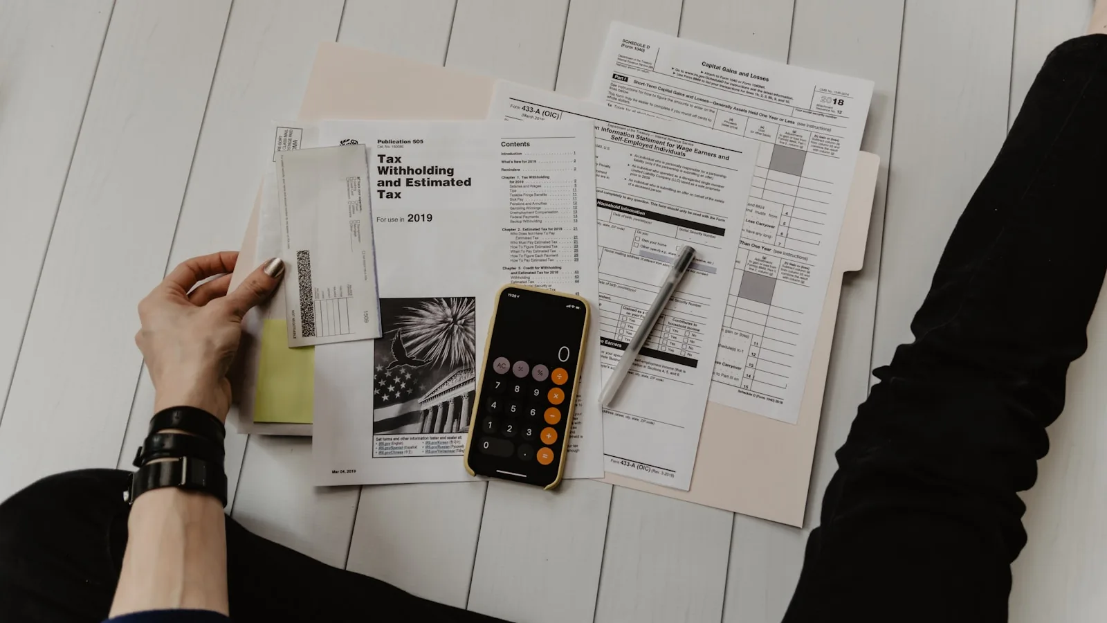 A hand holding a pen above paperwork and a calculator — the moment of deciding whether to appeal a refused NHS Continuing Healthcare funding decision.
