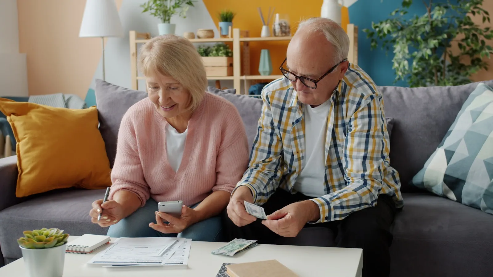 An older couple sitting at a kitchen table reviewing a Lasting Power of Attorney form together — the family conversation that should happen before any health crisis.