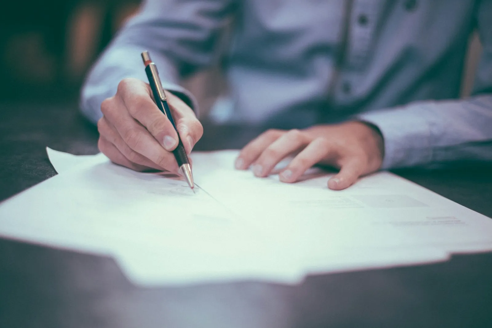 A family member at a desk with reading glasses, drafting a Mandatory Reconsideration letter referencing PIP descriptor scoring — the typical setup for a DIY MR filing.