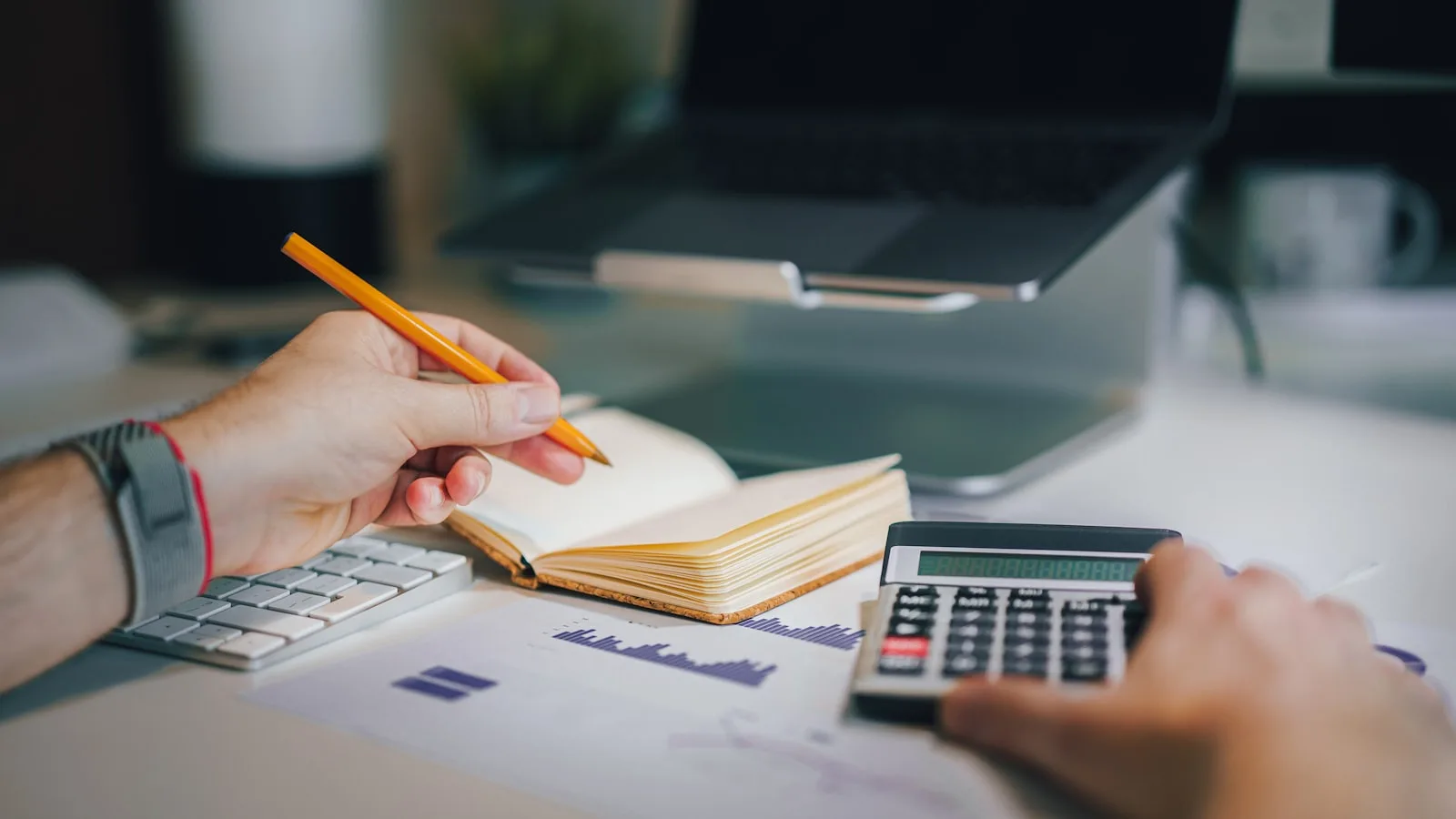 A calculator resting on a folder of care home invoices and financial paperwork, representing the maths of a retrospective NHS Continuing Healthcare reclaim and the interest the NHS adds.