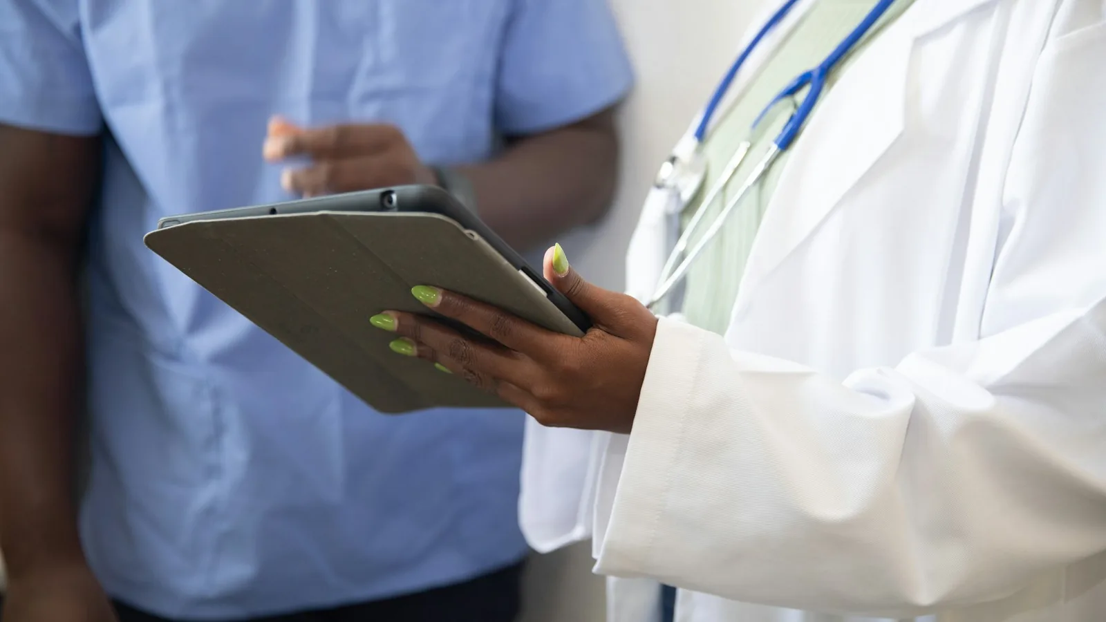 A clinician showing a paper form to a relative on a tablet — the Decision Support Tool is the NHS document that records evidence across 12 care domains during a Continuing Healthcare assessment.